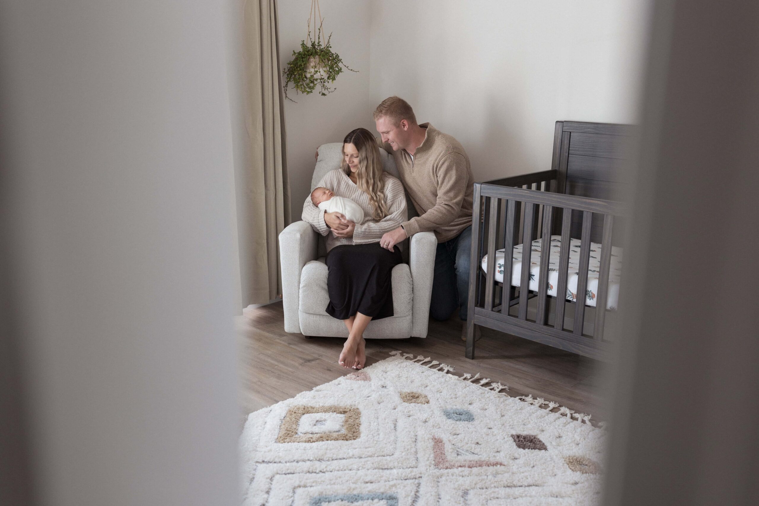 Picture of mom and dad in baby's nursery holding the newborn