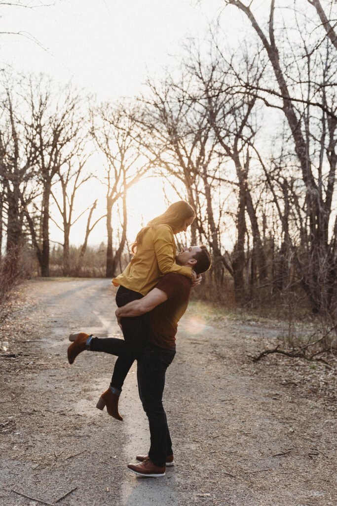 Engaged couple smiling and embracing in an open grassy field. 