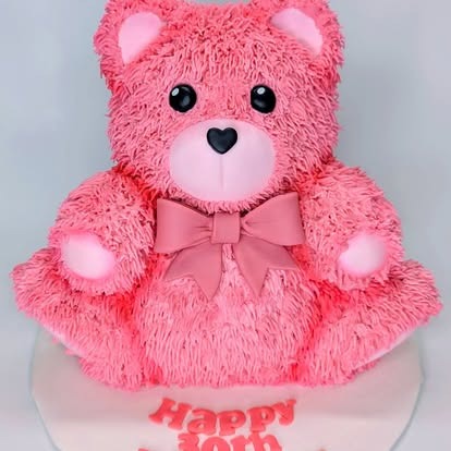 A 3D pink teddy bear-shaped cake with a bow and “Happy 30th” written on the base.