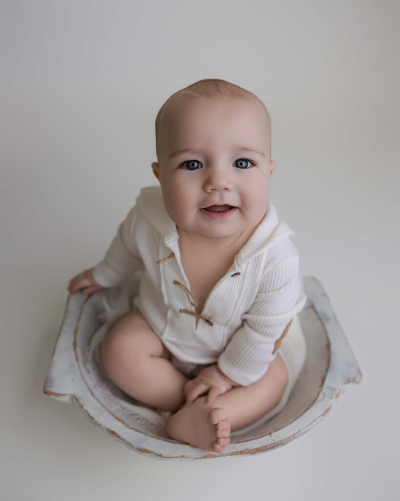 Baby sitting inside a vintage bowl during a minimalist indoor sitter session photoshoot.