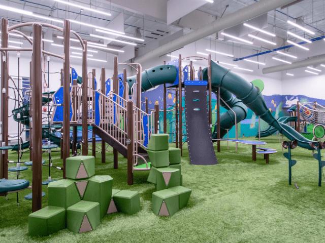 Indoor climbing and play area at Courts Plus Community Fitness featuring playground equipment, tunnels and slides for children.