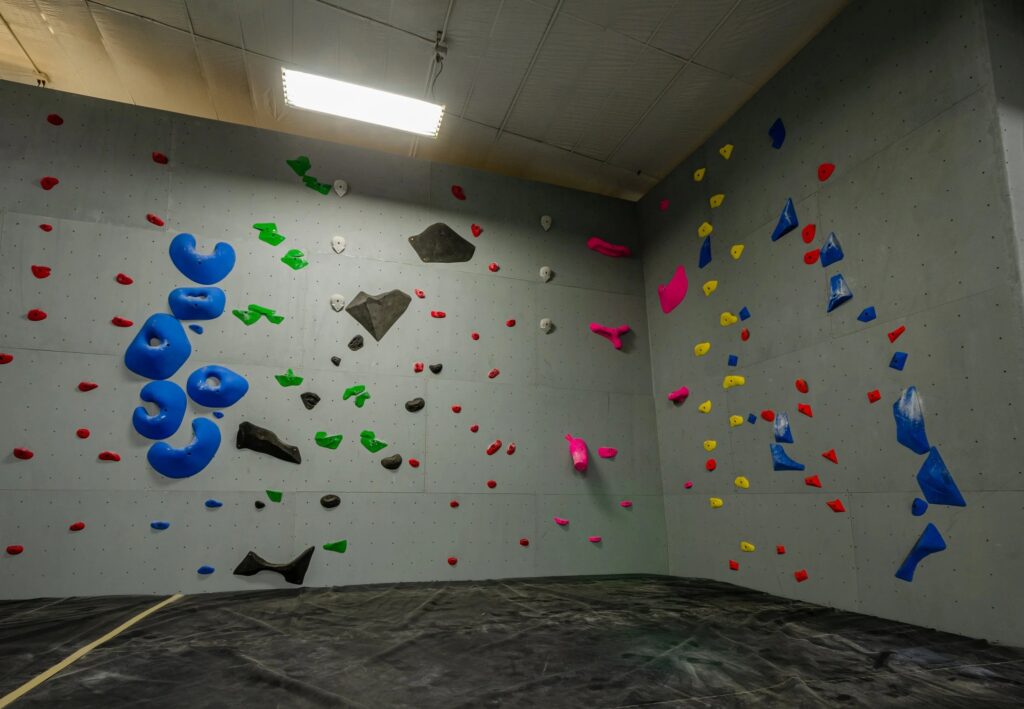 Indoor bouldering and climbing wall at Fargo Climbing with colorful climbing holds and padded flooring for indoor rock climbing.