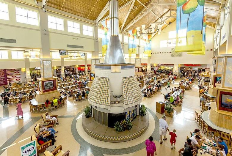 Food court and shopping area inside West Acres Mall with restaurants, seating and shoppers.