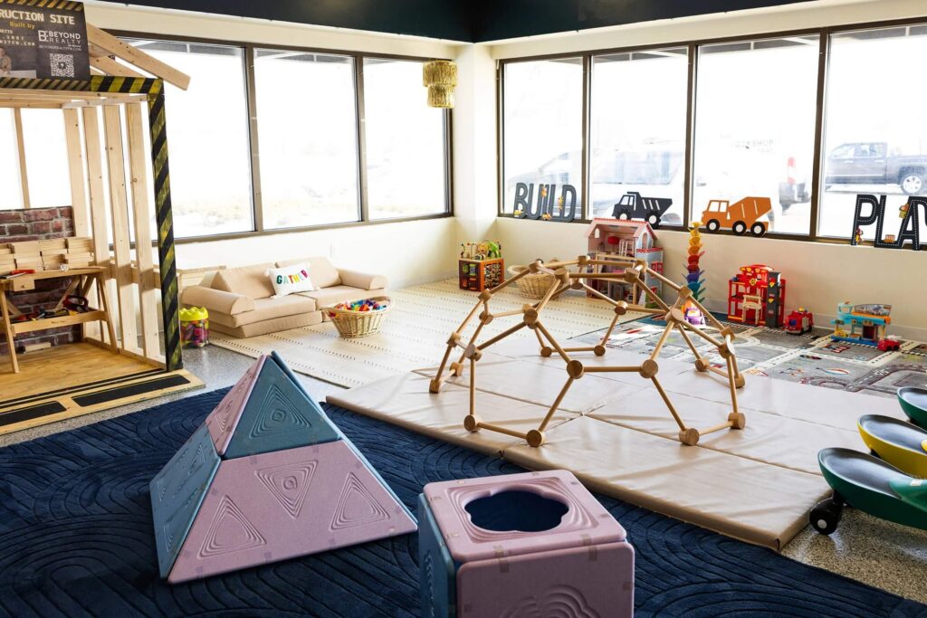 Modern indoor play cafe at Gathered FM featuring climbing toys, building stations, toddler play spaces and seating for parents.