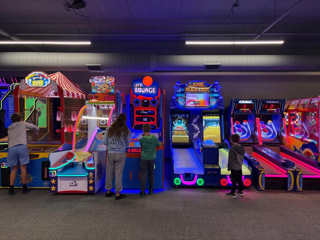 Kids playing arcade games inside the entertainment center at Levity featuring neon-lit arcade machines and family activities.